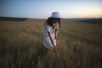 France, Woman in white dress and hat in field
