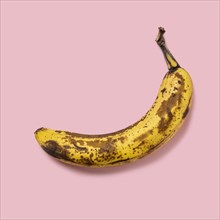 Overripe banana on pink background