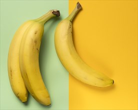 Three ripe bananas on green and yellow background
