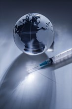 Glass globe and syringe on gray background