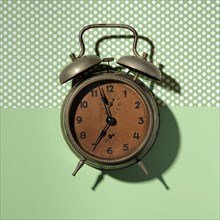 Vintage alarm clock on green background