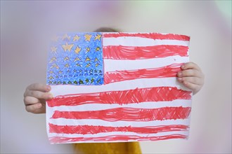 Boy (4-5) holding US flag drawn on paper