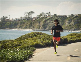 USA, California, Dana Point, Man running on road by coastline