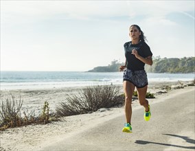 USA, California, Dana Point, Woman running on road by coastline
