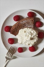Chocolate cake with whipped cream and raspberries on plate