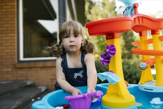 Portrait of toddler girl (2-3) playing with water in garden