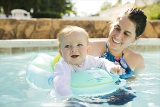 Mother with baby son (6-11months) playing in outdoor swimming pool