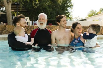 Multigeneration family with kids ( 2-3, 6-11 months) standing in outdoors swimming pool