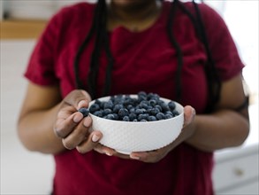 Close up of woman holding bowl with blueberries