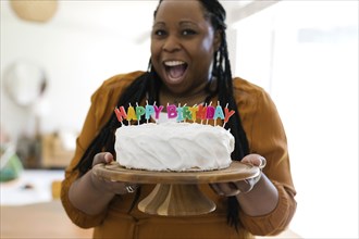Portrait of smiling woman holding birthday cake with candles