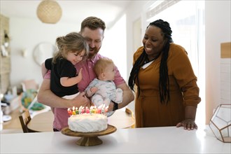 Woman and man with kids (2-3, 9-11 months) celebrating birthday at home