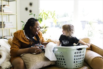 Woman playing with little girl (2-3) sitting in laundry basket
