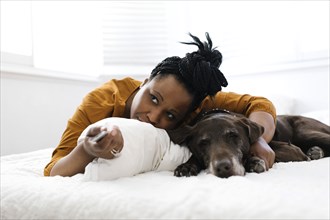 Woman lying on bed with dog and watching tv