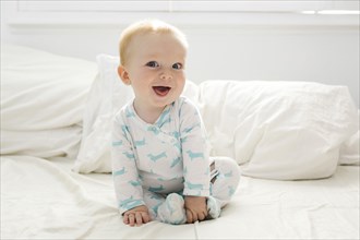 Baby boy (6-11 months) lying on bed