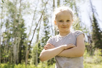 USA, Utah, Uinta National Park, Portrait of girl (6-7) with arms crossed in forest