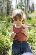 USA, Utah, Uinta National Park, Girl (6-7) holding blade of grass in forest