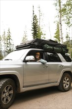 Woman sitting in off road car with tent on roof