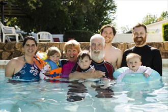Portrait of multigeneration family posing in swimming pool