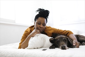 Sad woman lying on bed with dog
