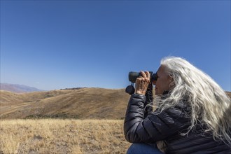 USA, Idaho, Bellevue, Woman looking through binoculars in desert
