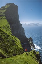 Denmark, Faroe Islands, Klaksvik, Trollanes, Woman standing on cliff and looking at ocean