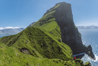 Denmark, Faroe Islands, Klaksvik, Trollanes, Woman standing on cliff and looking at Kallur Lighthouse