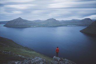 Denmark, Faroe Islands, Klaksvik, Woman standing on rock and looking at fjord