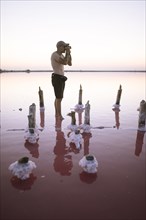 Ukraine, Crimea, Man standing in salt lake and taking photos