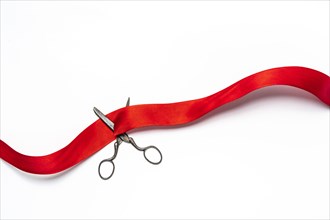 Studio shot of old fashioned scissors cutting red ribbon