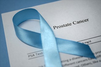 Studio shot of prostate cancer document and blue ribbon