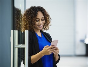 Smiling businesswoman using smart phone in office