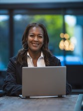 Portrait of smiling businesswoman sitting at desk with laptop in office