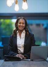 Portrait of smiling businesswoman sitting at desk with laptop in office