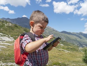 Boy with smartphone hiking in mountains