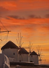 Whitewashed windmills against sunset sky