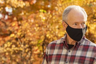 Portrait of senior man wearing Covid protective mask outdoors in fall