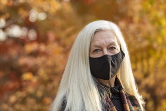 Portrait of senior woman wearing Covid protective mask outdoors in fall