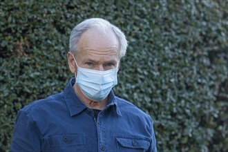 Outdoor portrait of senior man wearing covid protective mask outside in fall
