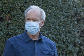 Outdoor portrait of senior man wearing covid protective mask outside in fall
