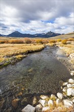 Landscape with stream and mountains in distance