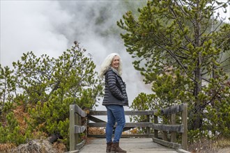Senior female tourist standing on wooden observation point in Yellowstone National Park