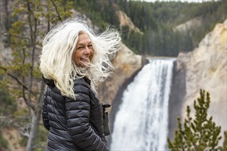 Senior female tourist standing at Yellowstone Falls above the Grand Canyon in Yellowstone National Park