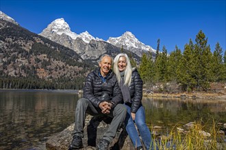 Outdoor portrait of senior couple sitting on rock by Taggart Lake in Grand Teton National Park