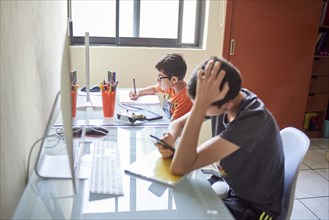 Two boys learning at desk at home during Covid-19 lockdown