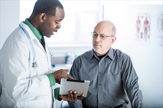 Doctor with digital tablet talking to patient