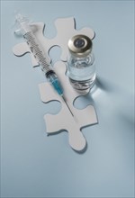 Vial of Covid-19 vaccine and syringe on jigsaw puzzles