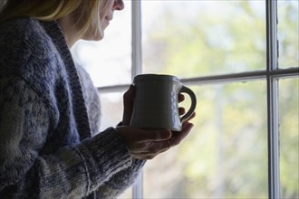 Woman holding mug and looking out window
