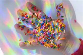 Hand holding sprinkles with colorful reflections