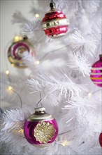 Pink ornaments on white Christmas tree