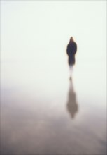 Woman reflected in wet sand on beach